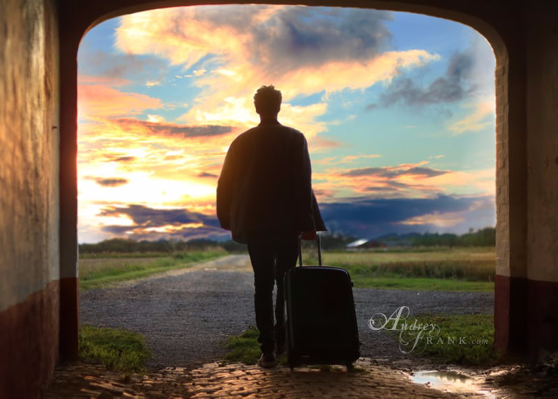 A man sillhouetted in a doorway with a suitcase embarking on a journey

