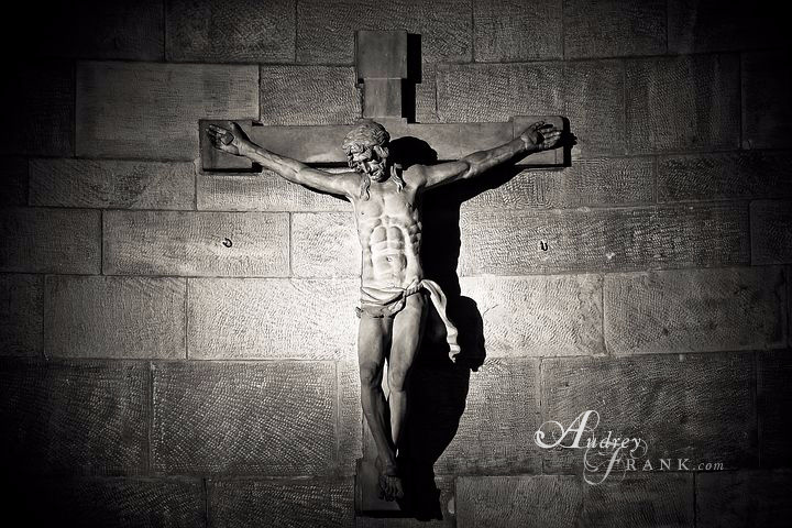 A picture of Jesus hanging on the cross against a stone wall backdrop.
