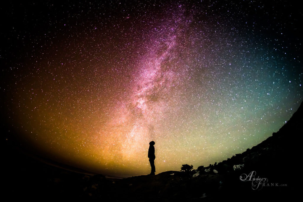 person standing at night looking up at the milky way.