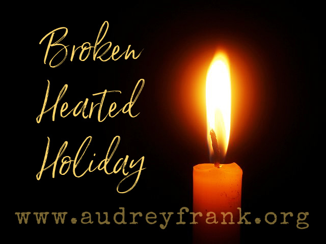 a candle glowing in the darkness with the words Broken Hearted Holiday