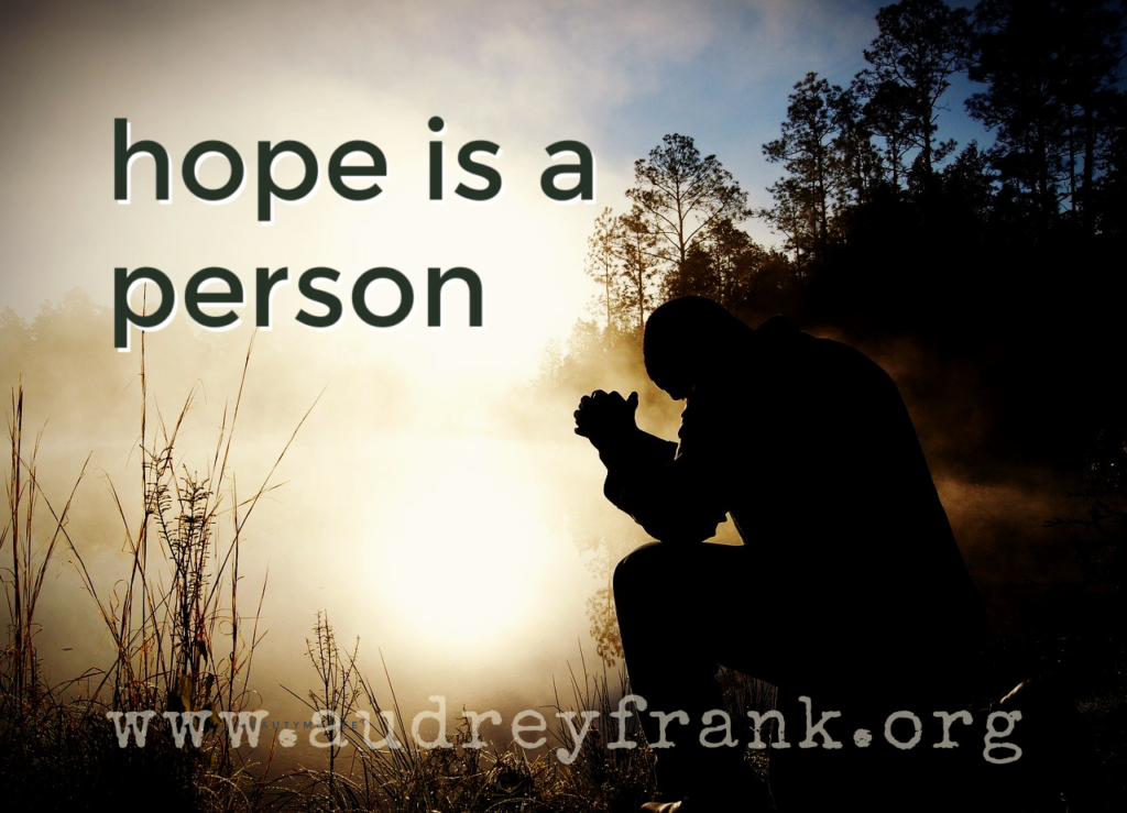 a person sits in prayer in silhouette, with the words hope is a person describing the subject of the post