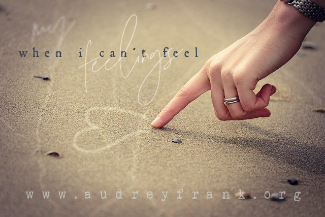 A finger drawing a heart in the sand.