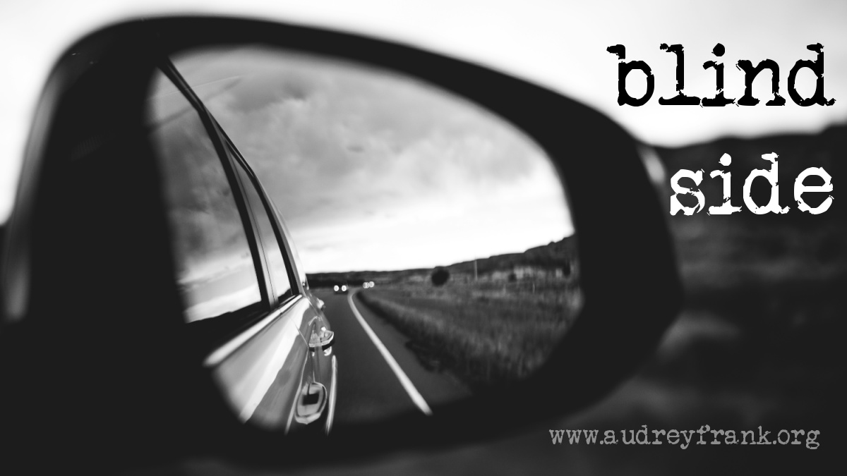 A side mirror on a car displaying the blind side of a car with the words "Blind Side" describing the subject of the post.